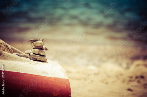Zen stone on an old boat in a sandy beach, Crete, Greece