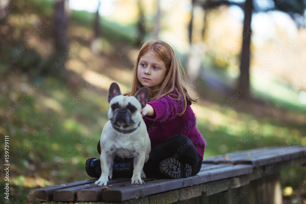 Children and dogs outdoors. Beautiful and happy redhead girl enjoying and playing in autumn park with her adorable French bulldog. Children and dogs outdoors. Beautiful and happy redhead girl enjoying and playing in autumn park with her adorable French bulldog.