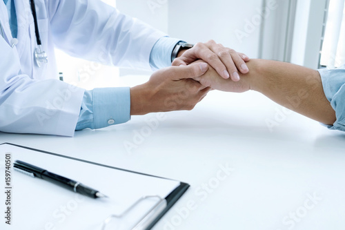 Doctor working with laptop computer and writing on paperwork. Hospital background.