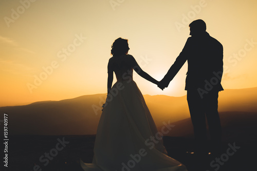 Wedding couple posing on sunset at wedding day. Bride and groom in love