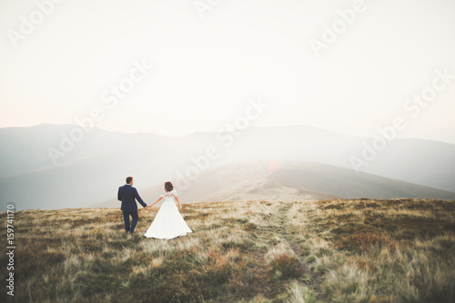 Beautiful wedding couple posing on top of a mountain at sunset
