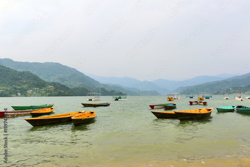 Fototapeta premium Boats hangared in Phewa Lake, Pokhara second largest freshwater lake in Nepal, famous for the reflection of Machhapuchhre & other mountain peaks on its surface.