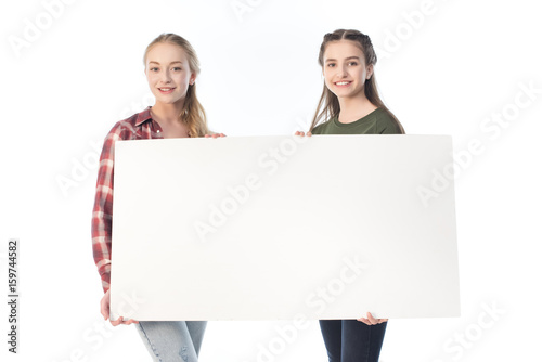 smiling teenage girls holding blank banner isolated on white