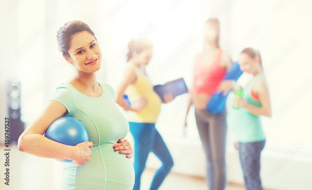 happy pregnant woman with ball in gym