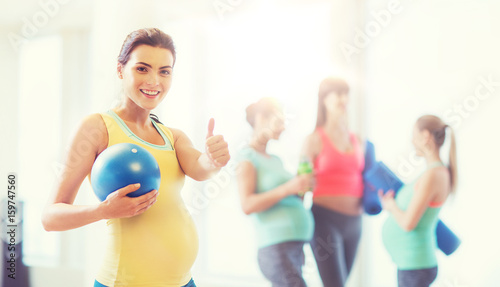 pregnant woman with ball in gym showing thumbs up 