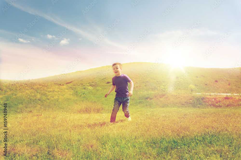 happy little boy running on green field outdoors