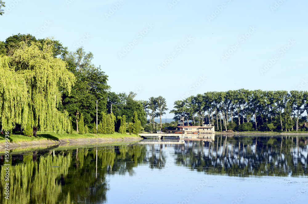 Obraz premium Lake, old pier, green trees, blue sky
