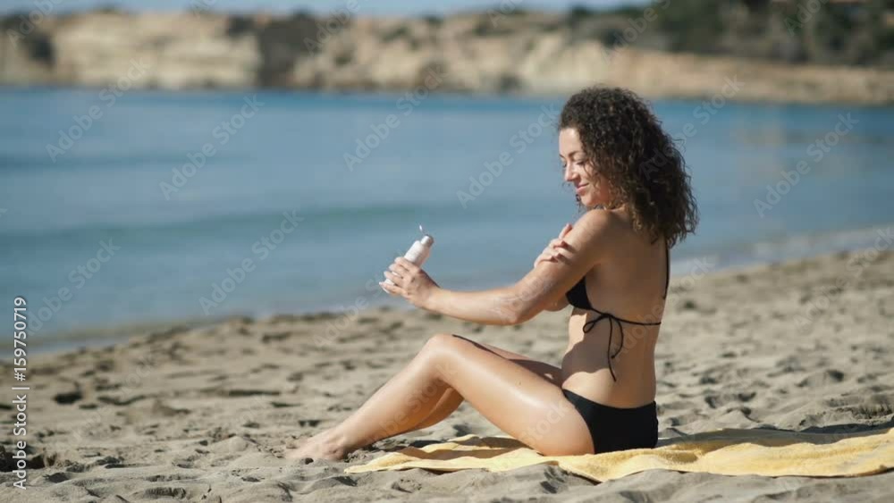 Young girl smears sunscreen on hands on the beach Young girl smears sunscreen on hands on the beach