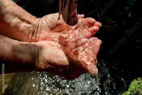 Hände von erwachsener Frau in frischem klaren Quellwasser