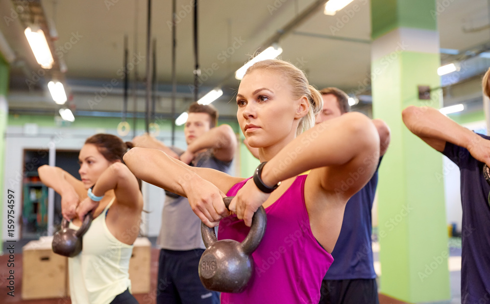 group of people with kettlebells exercising in gym group of people with kettlebells exercising in gym