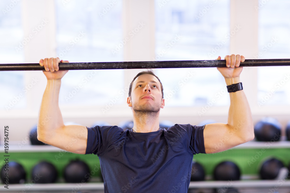 Naklejka premium man exercising on bar and doing pull-ups in gym