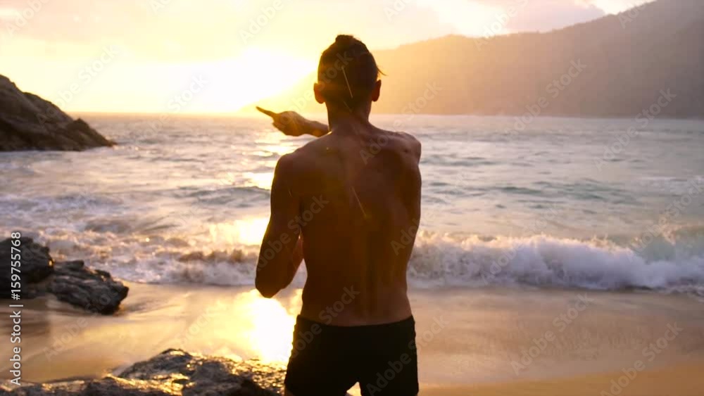 Athletic young naked torso male sings a song on ocean coast at sunset. Athletic young naked torso male sings a song on ocean coast at sunset.