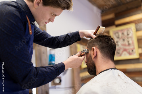 man and barber with trimmer cutting hair at salon