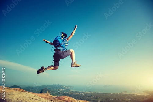 cheering woman jumping on rocky mountain top