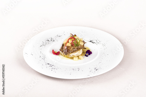 Luxurious dish with duck liver, pineapple and mango pieces, sweet sauce, placed on toasted bread, decorated with eatable flowers and red and green leafs, placed on white plate, light background, isola
