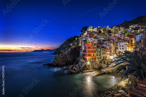 Fototapeta Naklejka Na Ścianę i Meble -  Riomaggiore fisherman village at sunset. Riomaggiore is one of five famous colorful villages of Cinque Terre in Italy, suspended between sea and land on sheer cliffs.