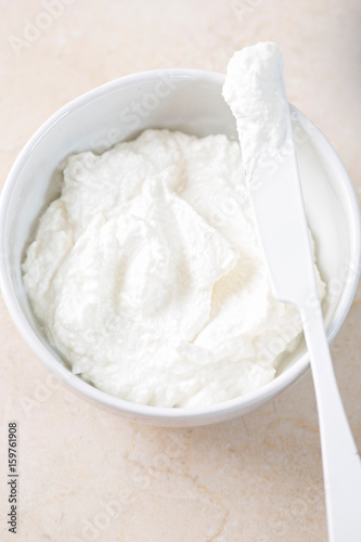 Fresh ricotta cheese in bowl with knife 