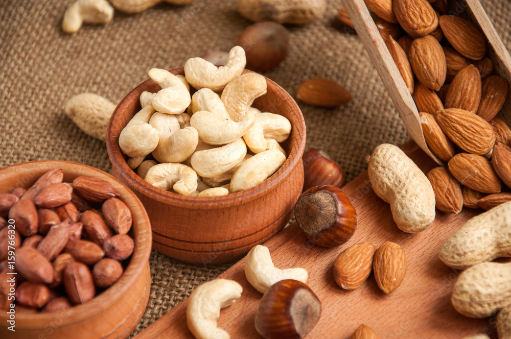 Almonds, cashew and hazelnuts in wooden bowls on wooden and burlap, sack background Almonds, cashew and hazelnuts in wooden bowls on wooden and burlap, sack background