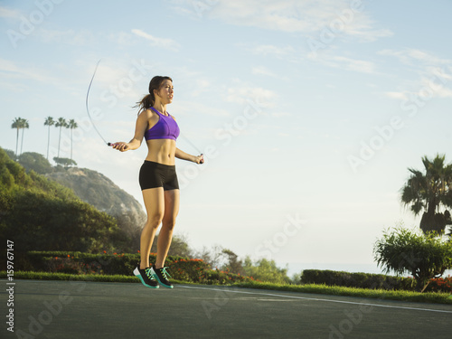 Young woman jumping rope in park photo