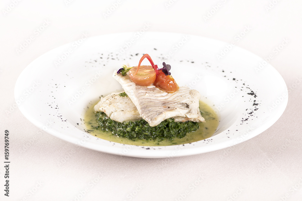 Perch fillet with spinach, sauce and tomato, decorated with eatable flowers and red leafs, placed on white plate, light background, isolated Perch fillet with spinach, sauce and tomato, decorated with eatable flowers and red leafs, placed on white plate, light background, isolated