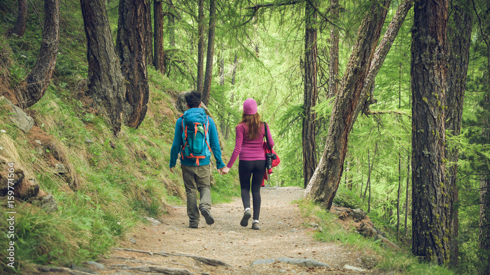 A couple hikers Hiking with backpacks walk along a beautiful mountain area holding hands . The concept of active rest. Switzerland 2017