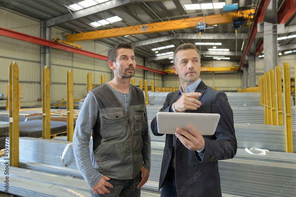 supervisor and manual worker using digital tablet in metal industry supervisor and manual worker using digital tablet in metal industry