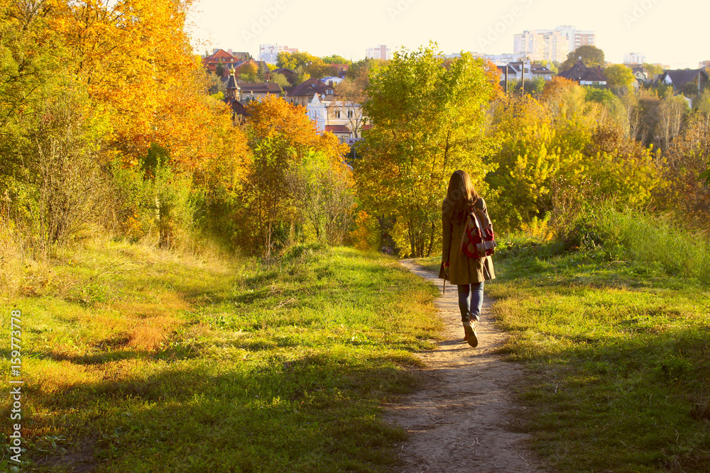 Young adult woman walking over autumn background.Shot of an attractive young woman in the park on an autumn day.