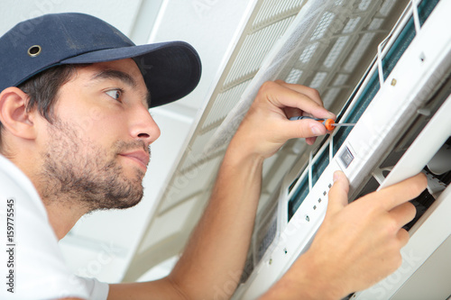 Canvas Print focused handyman testing air conditioning on the wall