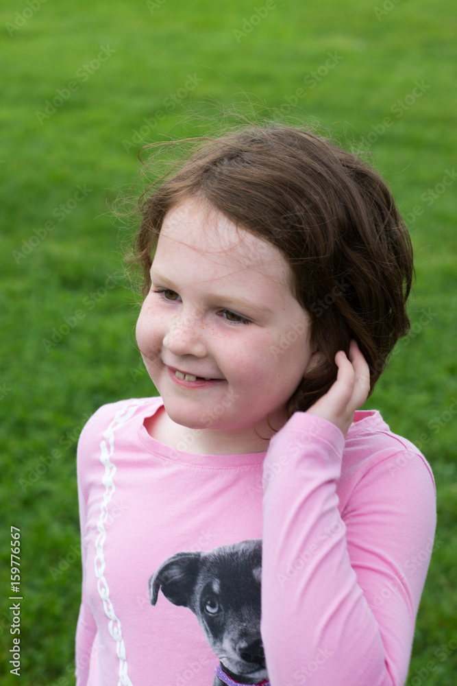 Young girl outside with hand in her hair Young girl outside with hand in her hair