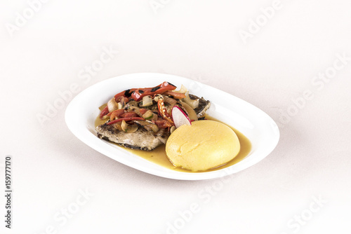 Brine fish plate with vegetables, chili and polenta, placed on white plate, light background, isolated