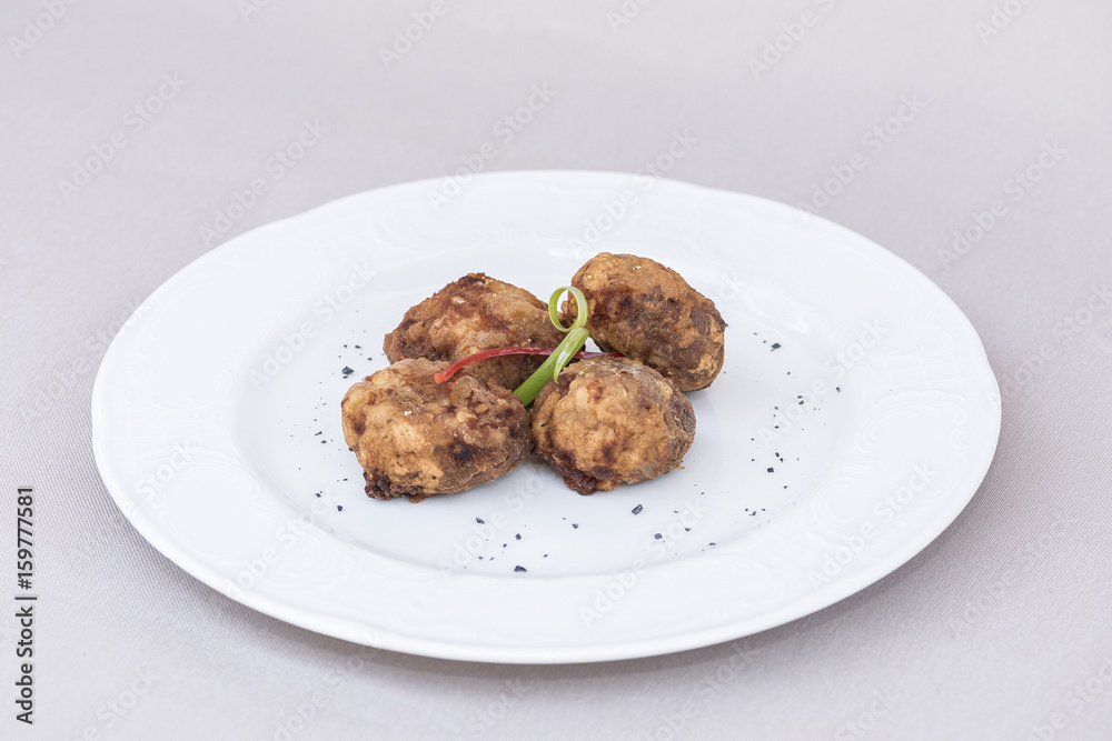 Fried pane sweetbreads, decorated with herbs, isolated on light background, white plate Fried pane sweetbreads, decorated with herbs, isolated on light background, white plate