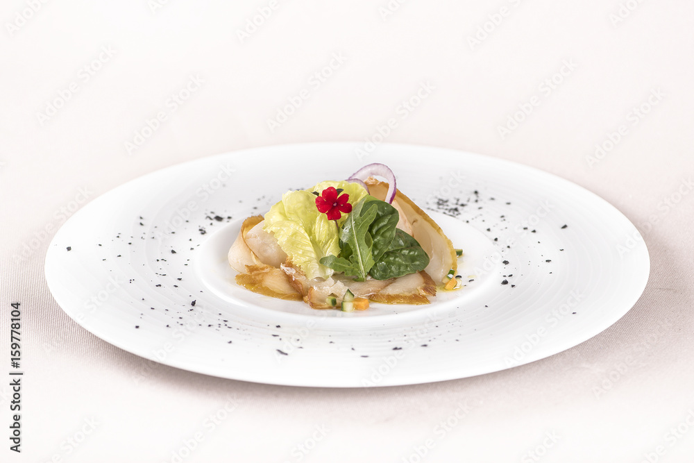 Fresh appetizer with smoked white fish, rucola, baby spinach and green salad, with red eatable flowers, placed on white plate, light background, isolated