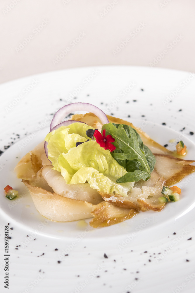 Fresh appetizer with smoked white fish, rucola, baby spinach and green salad, with red eatable flowers, placed on white plate, light background, isolated Fresh appetizer with smoked white fish, rucola, baby spinach and green salad, with red eatable flowers, placed on white plate, light background, isolated