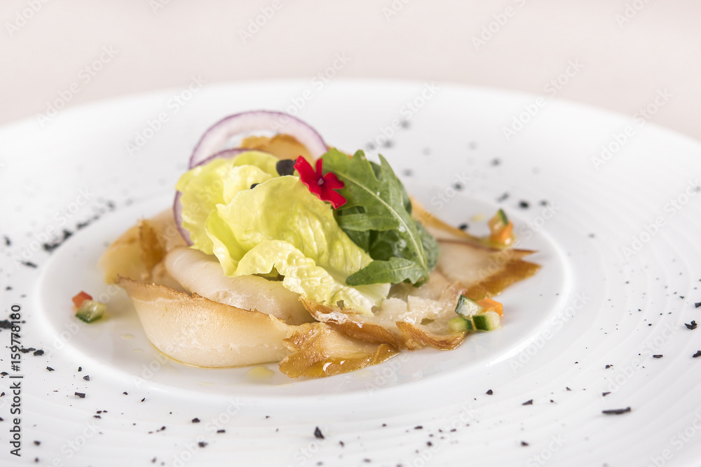 Fresh appetizer with smoked white fish, rucola, baby spinach and green salad, with red eatable flowers, placed on white plate, light background, isolated Fresh appetizer with smoked white fish, rucola, baby spinach and green salad, with red eatable flowers, placed on white plate, light background, isolated