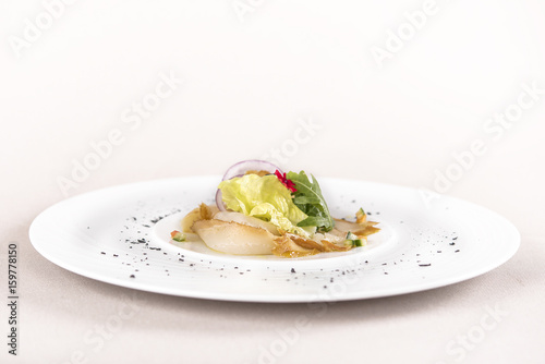 Fresh appetizer with smoked white fish, rucola, baby spinach and green salad, with red eatable flowers, placed on white plate, light background, isolated