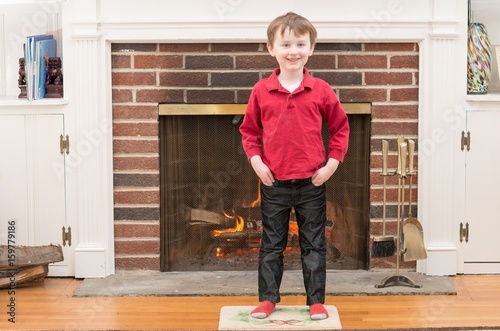 Portrait of a young smiling boy in front of a fireplace dressed for valentine's day