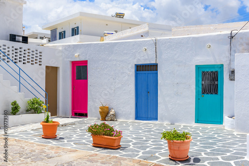 Tropical plants in pots in front of white house with colorful doors in Pollonia village. Milos,Cyclades Island. Greece © vivoo