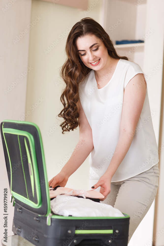 Girl collects a suitcase in a hotel room.