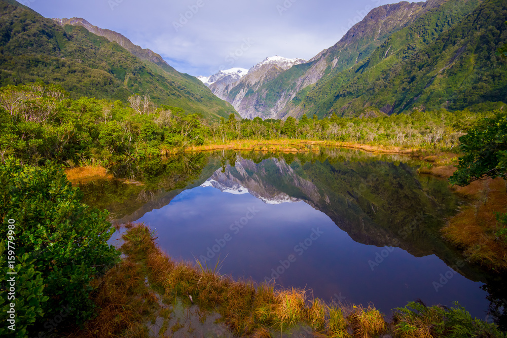 Small pond peters pond with reflection of mountain glacier Franz Josef Glacier in New Zealand