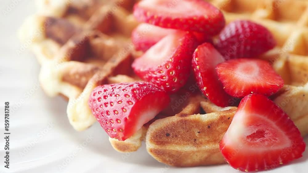 Adding fresh sliced berries to a homemade waffle Adding fresh sliced berries to a homemade waffle