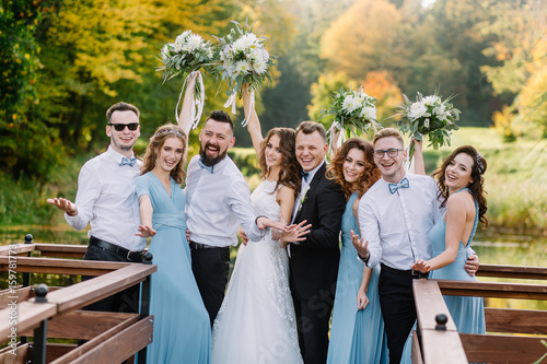 Positive, stylish guests at the wedding with a couple in love in the spring on the pier