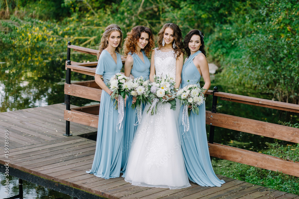 Stylish bridesmaids with a bride stand near the water