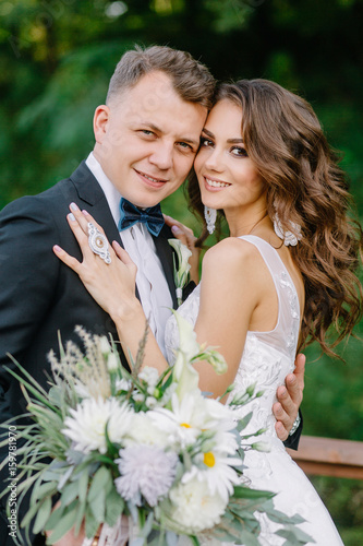 A nice, warm portrait of a stylish bridegroom and a charming bride in the nature