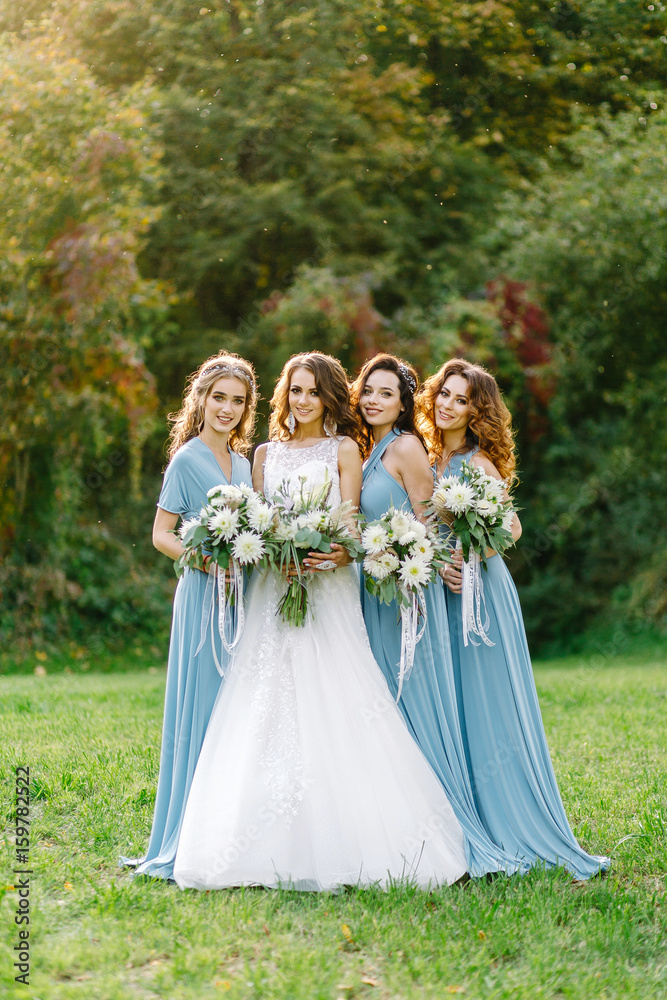 Stylish bridesmaids with a bride on a walk in the park
