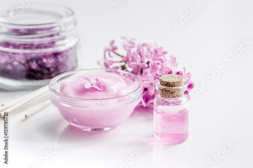 organic salt, cream, extract in lilac cosmetic set with flowers on white table background
