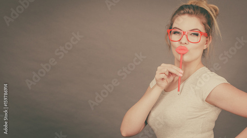 Happy woman holding fake lips on stick