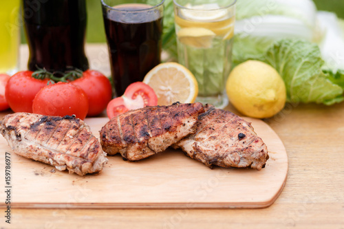 Сhicken breast grilled on a wooden Board. Chicken chili steak on the background with vegetables and black soda and lemonade, food photography