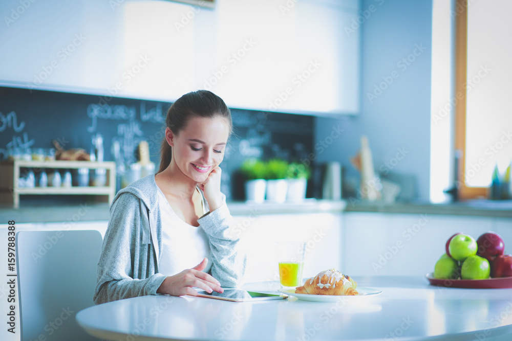 Young woman with orange juice and tablet in kitchen. Young woman with orange juice and tablet in kitchen.