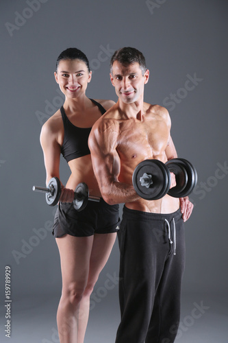 Athletic man and woman with a dumbells. Personal fitness instruc