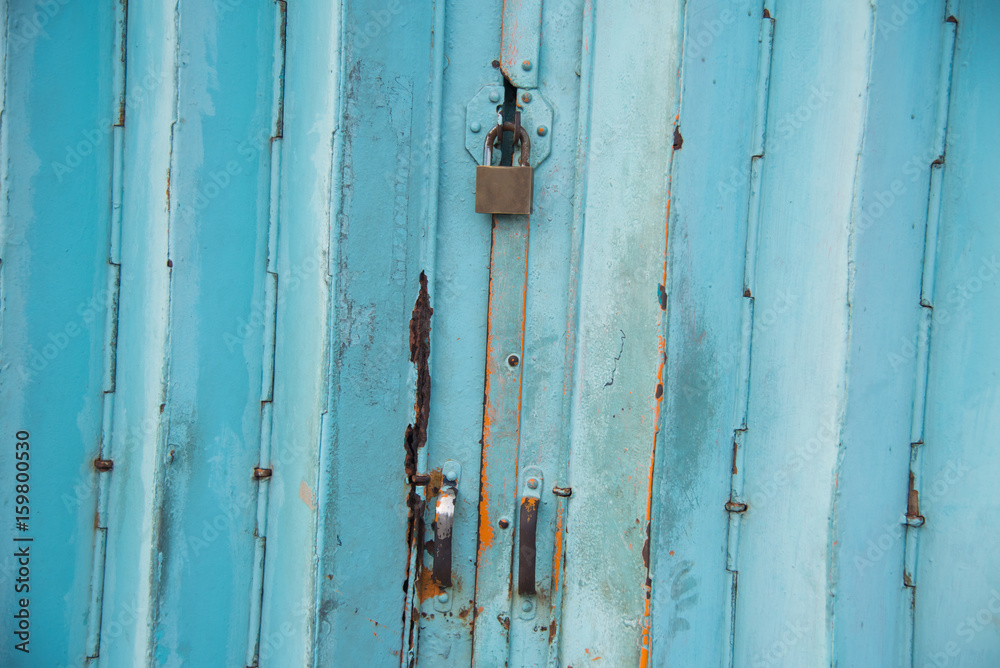 Mettalic lock without the key on the blue vintage door,Residential mettalic folding door with blue locking device installed Mettalic lock without the key on the blue vintage door,Residential mettalic folding door with blue locking device installed